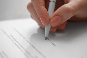 Woman signing documents on white background, closeup