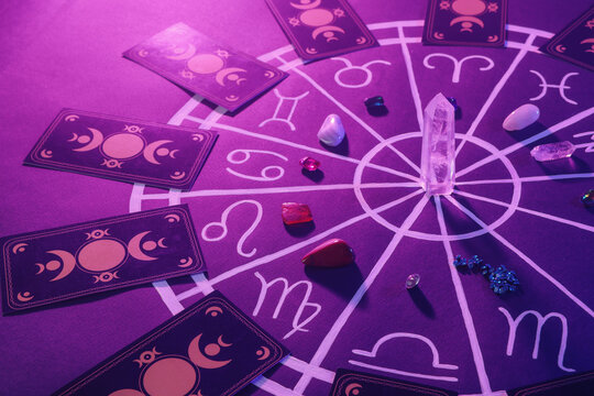 Natural stones for zodiac signs, tarot cards and drawn astrology chart on purple background. Color tone effect
