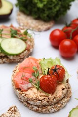 Crunchy buckwheat cakes with salmon, tomatoes and greens on white table, closeup