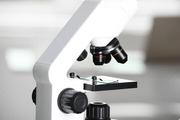 Modern medical microscope with glass slide on blurred background, closeup. Laboratory equipment