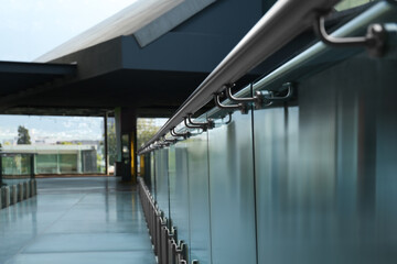 Glass barrier with metal handrail in modern building, closeup