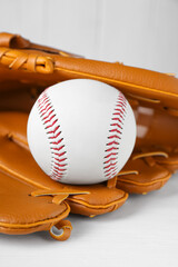 Leather baseball glove with ball on white wooden table