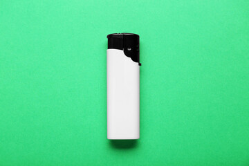 Stylish small pocket lighter on green background, top view