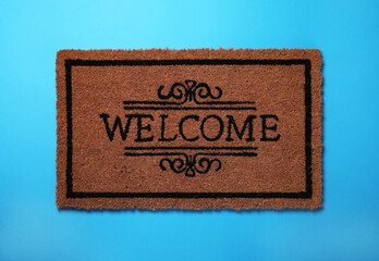 Doormat with word Welcome on light blue background, top view