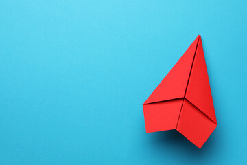 Handmade red paper plane on light blue background, top view. Space for text