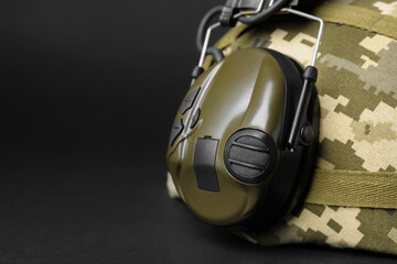 Helmet and tactical headphone on black background, closeup with space for text. Military training equipment