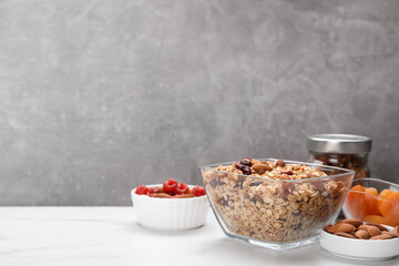 Tasty granola with nuts and dry fruits on white marble table. Space for text
