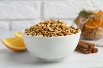 Bowl of dried orange zest seasoning, fresh fruit and cinnamon on white marble table