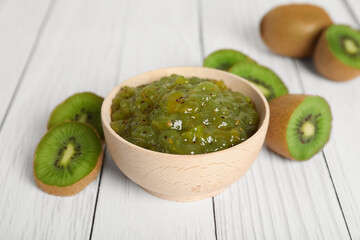 Bowl of delicious kiwi jam and fresh fruits on white wooden table