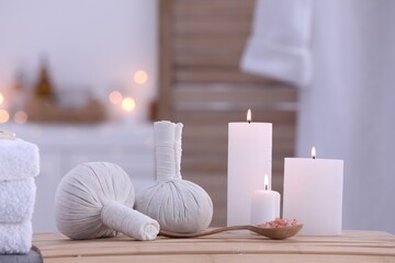 Fototapeta na wymiar Spa composition with burning candles and herbal bags on massage table in wellness center
