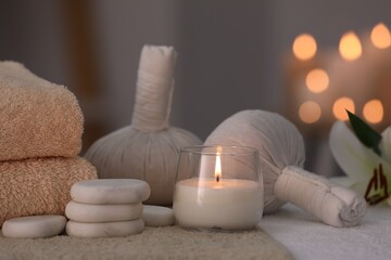 Fototapeta na wymiar Spa composition with burning candle and herbal bags on massage table in wellness center