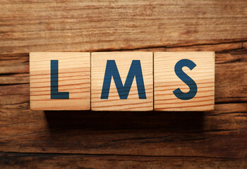 Learning management system. Cubes with abbreviation LMS on wooden background, top view