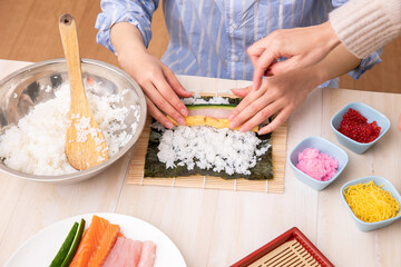 Obraz na płótnie Canvas 手巻き寿司を巻く女性の手元　cooking