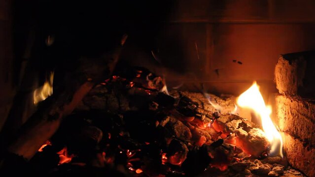 A Man Moving Burning Charcoal and Firewood using a Rake in a Fireplace. Close Up. 4K Resolution.