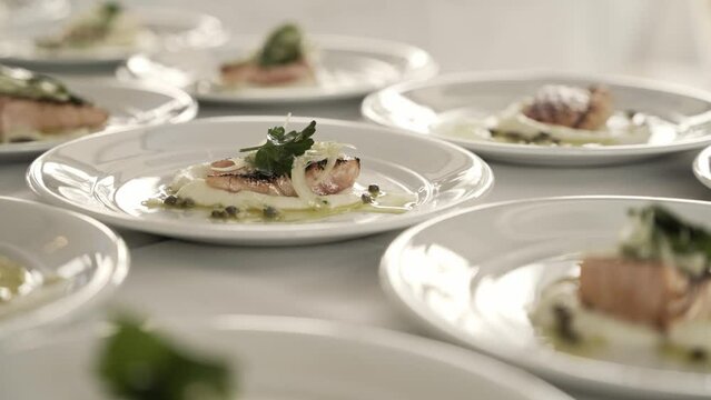 Master chef preparing delicious salmon meal in white plates, close up view