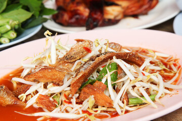 papaya salad with bean sprouts Crispy fish and pork crackling on wood table, selective focus
