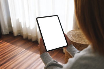 Mockup image of a woman holding digital tablet with blank desktop screen at home