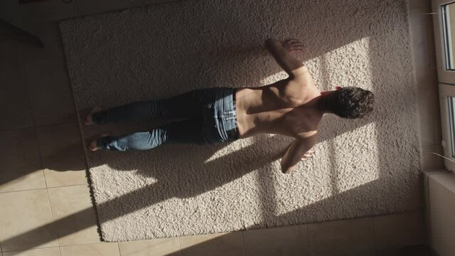 Portrait of man with tablet doing push-ups workout exercise indoors at home. Top view
