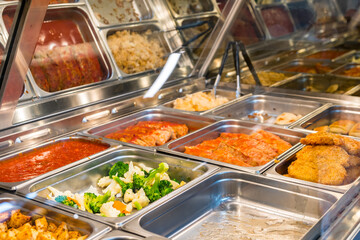 Hot and ready fresh buffet food steel trays under warming light background