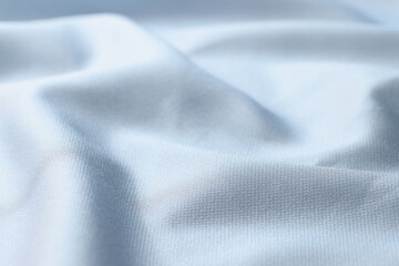 Fototapeta na wymiar Waved light blue silk fabric background. Close up of satin textile.