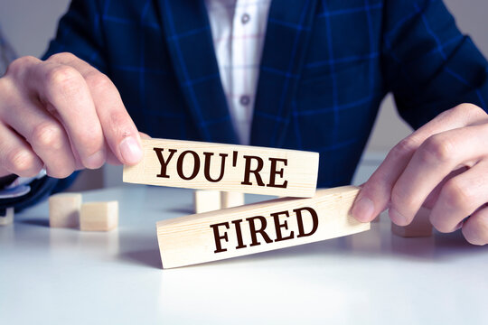 Closeup on businessman holding a wooden block with "You're fired", Business concept
