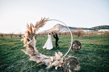 Outdoor wedding in nature. The concept of a wedding for two. Round arch with pompa grass against...