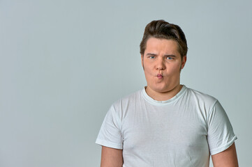 a man puffing out his cheeks with a funny face on a gray background, emotions