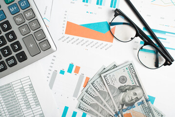 Financial documents, money, calculator, glasses and pencil on desktop. Business flat lay