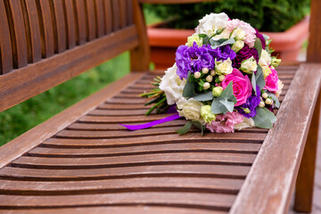 the brides wedding bouquet lies on a wooden bench. Copy space