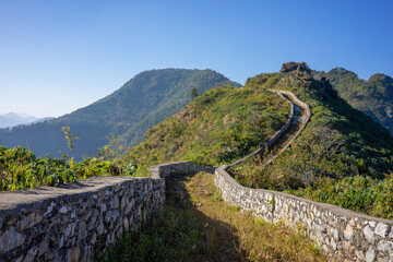 Curving path with dry stone wall leads over the mountains and hills at Bandipur Nepal on a sunny...