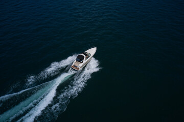 Big expensive motor boat fast moving diagonally on dark water drone view