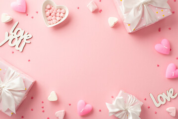 Valentine's Day concept. Top view photo of present boxes heart shaped saucer with sprinkles candles marshmallow and inscriptions love on isolated pastel pink background with blank space in the middle