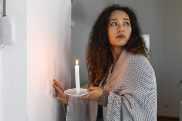 Energy crisis. Hand in complete darkness holding a candle trying to turn on light during a power...