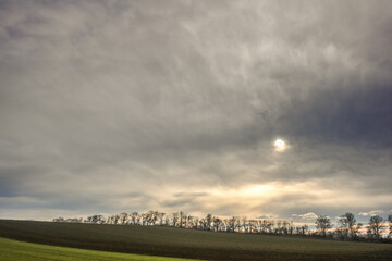 wonderful dense gray clouds with sun in a landscape with fields