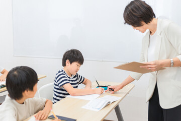 Fototapeta premium 小学生に勉強を教える笑顔の塾講師・先生（夏期講習・日本人女性） 