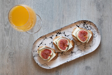 Orange juice and Sandwich with figs and cheese on a marble plate