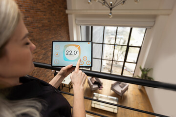 young woman using smart home app to control light turning on with tablet pc