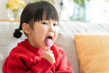 棒付きキャンディーを舐める子供（飴・お菓子）