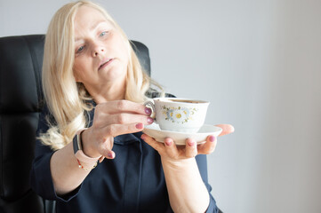 Woman holding a cup of coffee with a saucer. Selective focus on the cup