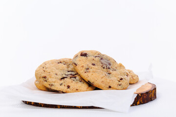 Homemade stacked chocolate chip cookies on wooden plate and white background