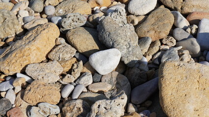 Cobble pieces of marble rock near water edge in Caesarea Maritima National Park, Israel.