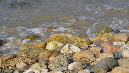 Cobble pieces of marble rock near water edge in Caesarea Maritima National Park, Israel.