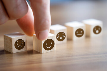 Men holding wooden block with happy face emoticon on it. 