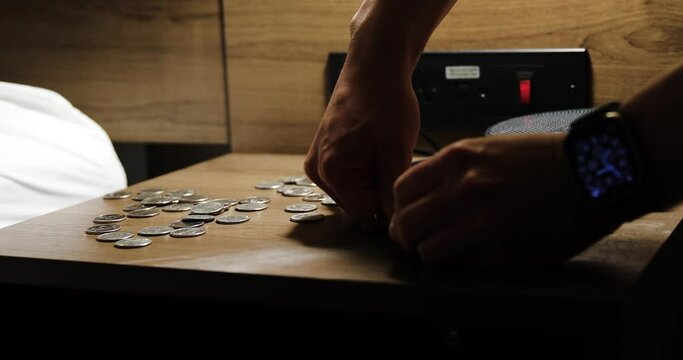Crushing up a pill with a spoon on a bedside table in a hotel with a room key card and change on desk