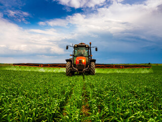Scientific crop protection with tractor-applied herbicides, pesticides, and fungicides, farmer in wheat fields ensuring plant health
