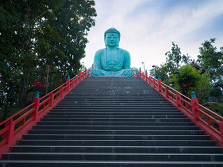 Great Buddha or Kamakura Daibutsu statue at midday. The ornate long temple stairs. Famous big Buddha statue inside Wat Phra That Doi Phra Chan temple. The most important travel destination in Lampang  © daphnusia