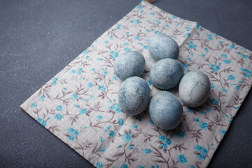 Easter eggs DIY painted blue on grey wooden background with kitchen towel. Copy space. Happy Easter concept