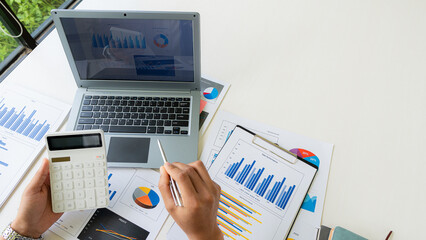 Hand of a business man using a calculator to check financial accounts, check expenditures and company budget. Female accountant calculating while working analyzing business reports at work