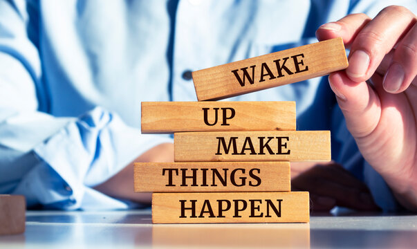 Closeup on businessman holding a wooden block with "Wake up, make things happen"