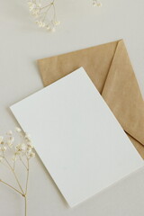 Greeting card mockup, envelope and  dried gypsophila flowers twigs on beige background top view...